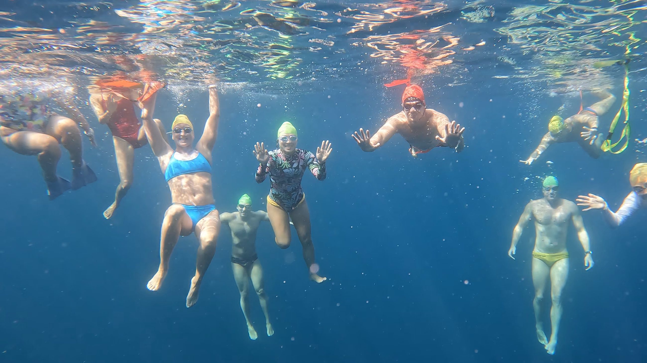 A group swimming together in open water off Catalina Island, sunlight breaking through the surface above them